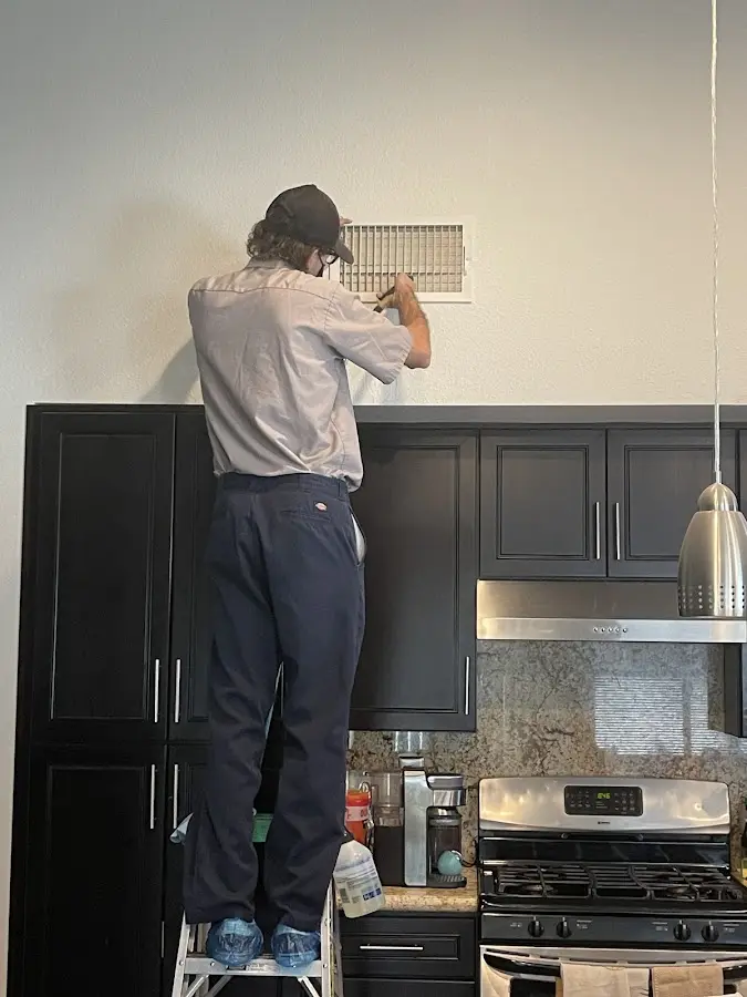 Technician inspecting an air vent during HVAC service in Haledon